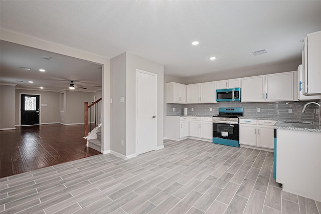 6723 Green Pear Ln, Houston, TX 77049 - kitchen with stainless steel appliances, light stone counters, light wood-style floors, tasteful backsplash, and open floor plan