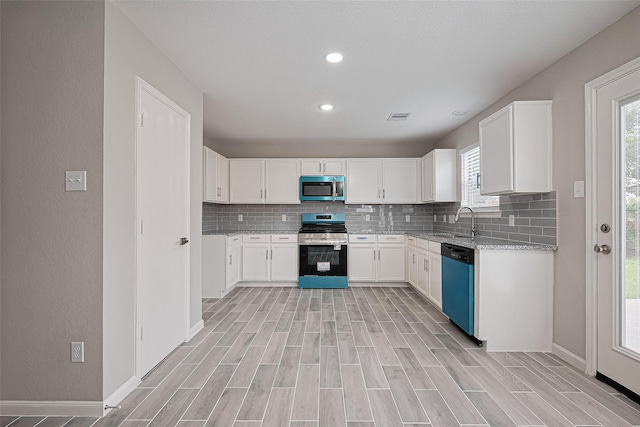 6723 Green Pear Ln, Houston, TX 77049 - kitchen featuring appliances with stainless steel finishes, decorative backsplash, light wood-style flooring, white cabinetry, and recessed lighting