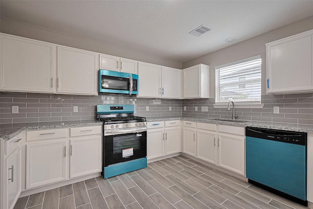 6723 Green Pear Ln, Houston, TX 77049 - kitchen with appliances with stainless steel finishes, white cabinetry, light stone counters, decorative backsplash, and light wood finished floors