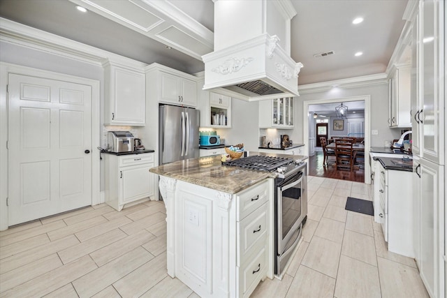 2408 Beall St, Houston, TX 77008 - kitchen featuring stainless steel appliances, white cabinets, a center island, glass insert cabinets, and ornamental molding