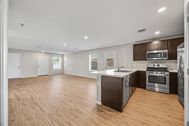 14403 Woodcott Warren Way, Rosharon, TX 77583 - kitchen with appliances with stainless steel finishes, dark brown cabinetry, a peninsula, open floor plan, and light countertops