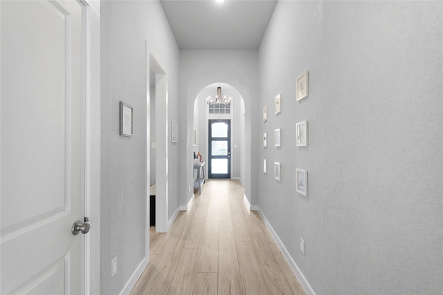 5122 Walnut Grove Ln, Manvel, TX 77578 - hallway with light wood-style flooring, a chandelier, arched walkways, and baseboards