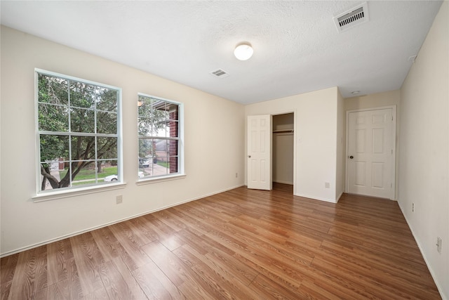 13814 Fort Nelson Dr, Houston, TX 77083 - unfurnished bedroom with light wood-style flooring, baseboards, a closet, and a textured ceiling