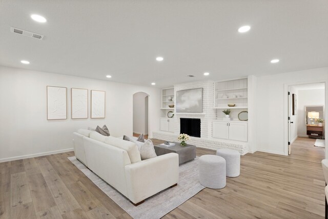 5302 Wigton Dr, Houston, TX 77096 - living area featuring arched walkways, recessed lighting, light wood-type flooring, built in features, and a brick fireplace
