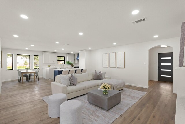 5302 Wigton Dr, Houston, TX 77096 - living room featuring arched walkways, recessed lighting, and light wood finished floors
