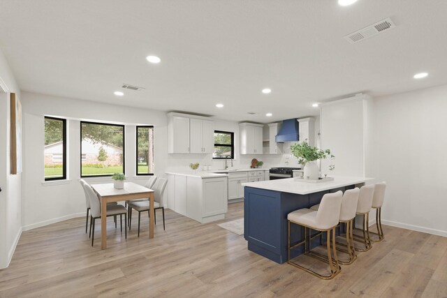5302 Wigton Dr, Houston, TX 77096 - kitchen featuring wall chimney range hood, a kitchen breakfast bar, a peninsula, light countertops, and stainless steel gas range oven