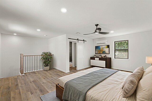 5302 Wigton Dr, Houston, TX 77096 - bedroom featuring a barn door, a wall mounted AC, wood finished floors, recessed lighting, and a ceiling fan