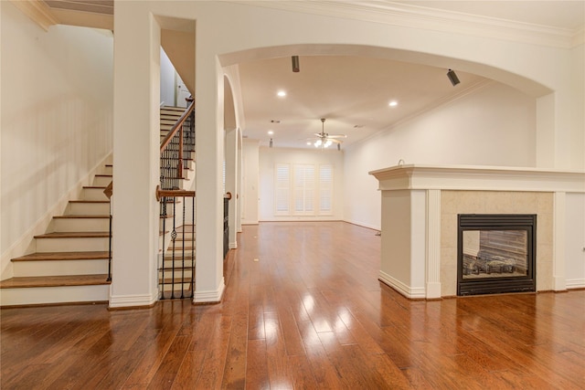 7115 Laguna Villas, Houston, TX 77036 - unfurnished living room featuring ceiling fan, stairs, hardwood / wood-style flooring, arched walkways, and a tiled fireplace