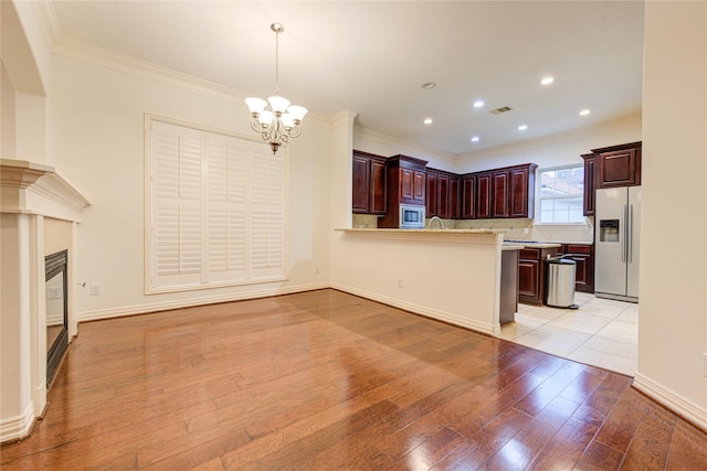 7115 Laguna Villas, Houston, TX 77036 - kitchen featuring refrigerator with ice dispenser, stainless steel microwave, ornamental molding, a chandelier, and light wood-style flooring