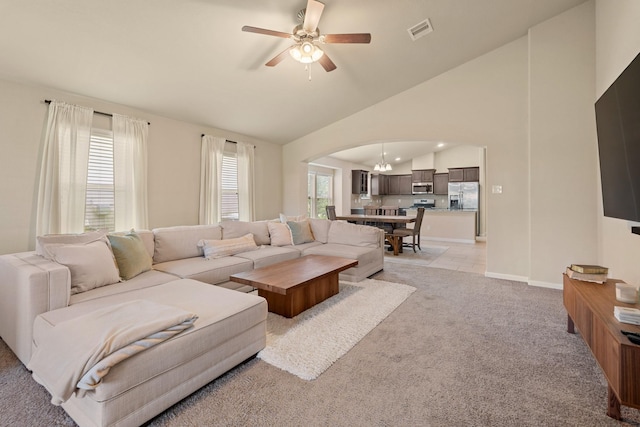 19110 Macallan Ln, Katy, TX 77449 - living room featuring arched walkways, a ceiling fan, light colored carpet, a chandelier, and high vaulted ceiling