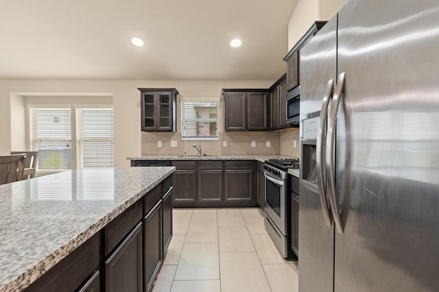 19110 Macallan Ln, Katy, TX 77449 - kitchen with stainless steel appliances, dark brown cabinets, light tile patterned floors, glass insert cabinets, and recessed lighting