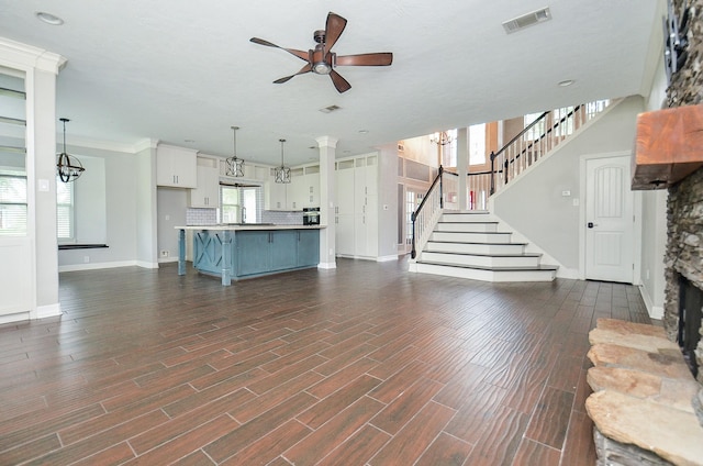 16210 S Temple Dr, Houston, TX 77095 - unfurnished living room featuring ceiling fan, a stone fireplace, dark wood-type flooring, stairway, and a chandelier