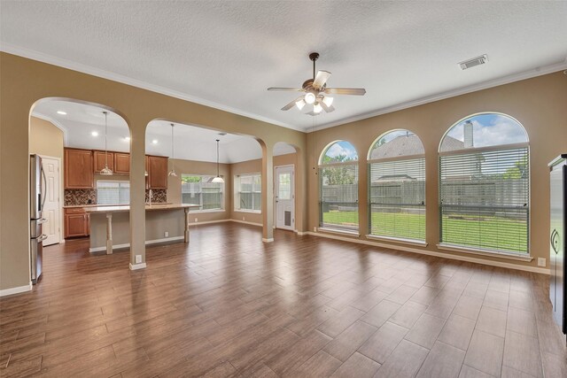 1431 Hidden Terrace Dr, Sugar Land, TX 77479 - unfurnished living room featuring ceiling fan, arched walkways, healthy amount of natural light, dark wood finished floors, and ornamental molding