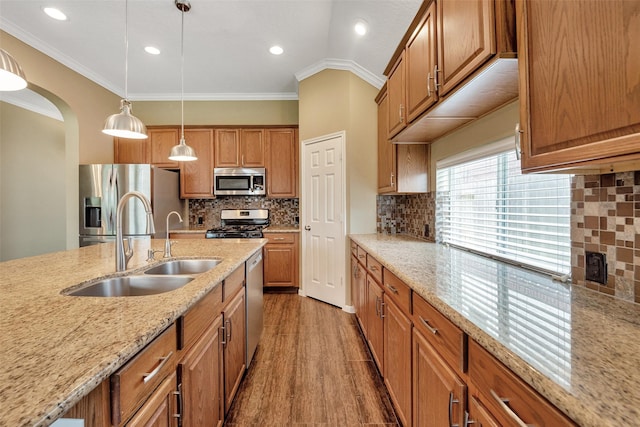 1431 Hidden Terrace Dr, Sugar Land, TX 77479 - kitchen with stainless steel appliances, brown cabinetry, decorative light fixtures, crown molding, and light stone counters