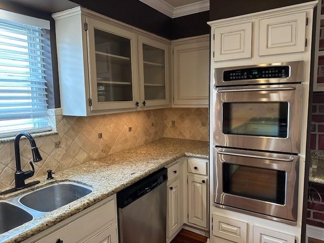 2907 Arrowhead Dr, Sugar Land, TX 77479 - kitchen with appliances with stainless steel finishes, ornamental molding, healthy amount of natural light, backsplash, and glass insert cabinets