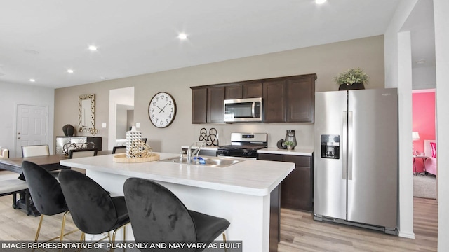 5446 Pinetree Crescent Ln, Spring, TX 77373 - kitchen with stainless steel appliances, light wood finished floors, light countertops, dark brown cabinets, and an island with sink