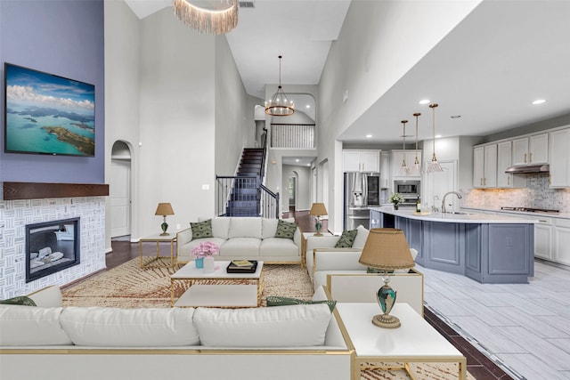 4511 Hickory Branch Ln, Sugar Land, TX 77479 - living room featuring a towering ceiling, stairs, a glass covered fireplace, a chandelier, and recessed lighting