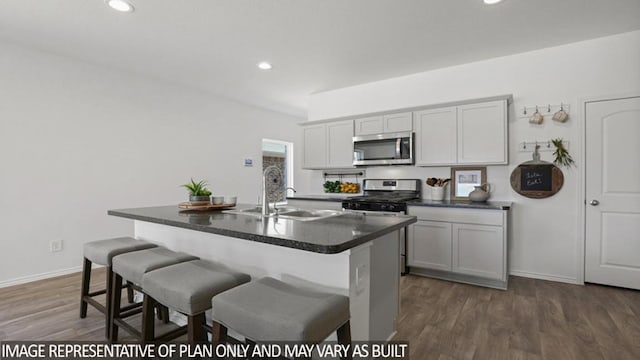 5442 Pinetree Crescent Ln, Spring, TX 77373 - kitchen featuring stainless steel microwave, range with gas stovetop, dark countertops, a kitchen breakfast bar, and dark wood-type flooring
