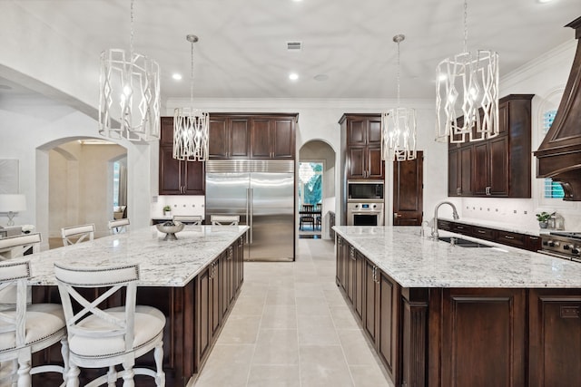 5201 Pine St, Bellaire, TX 77401 - kitchen featuring built in appliances, arched walkways, a spacious island, recessed lighting, and crown molding