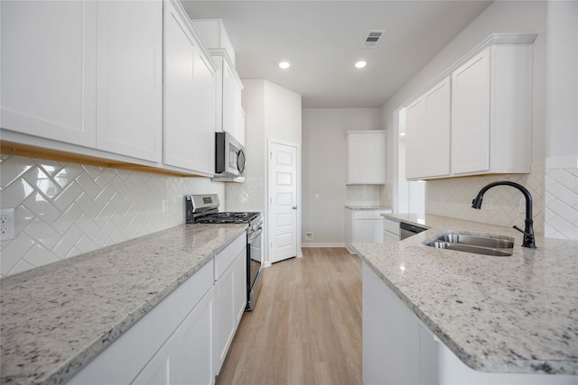 10919 Independence Rd, Cleveland, TX 77328 - kitchen featuring stainless steel appliances, light stone countertops, white cabinets, light wood finished floors, and backsplash