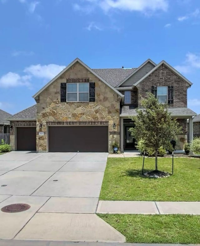9615 Emerald Briar Ln, Rosenberg, TX 77469 - view of front of home with stone siding, driveway, a front yard, roof with shingles, and a garage
