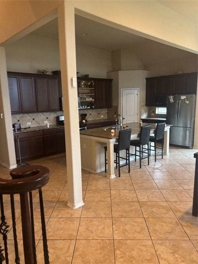 9615 Emerald Briar Ln, Rosenberg, TX 77469 - kitchen featuring freestanding refrigerator, tasteful backsplash, a kitchen breakfast bar, and light tile patterned flooring