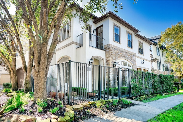 4035 Gramercy St, Houston, TX 77025 - townhome / multi-family property featuring a fenced front yard, stone siding, stucco siding, and a balcony