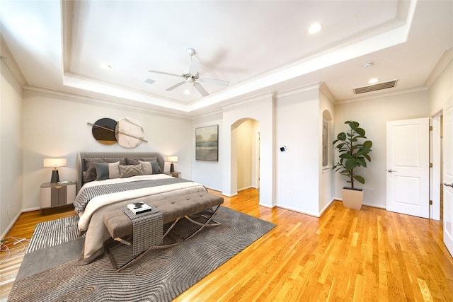 4035 Gramercy St, Houston, TX 77025 - bedroom featuring arched walkways, a tray ceiling, crown molding, light wood-style flooring, and recessed lighting