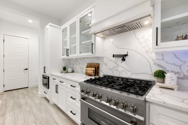 12 Rd 662, Dayton, TX 77535 - kitchen with stainless steel stove, custom range hood, decorative backsplash, white cabinetry, and light stone counters