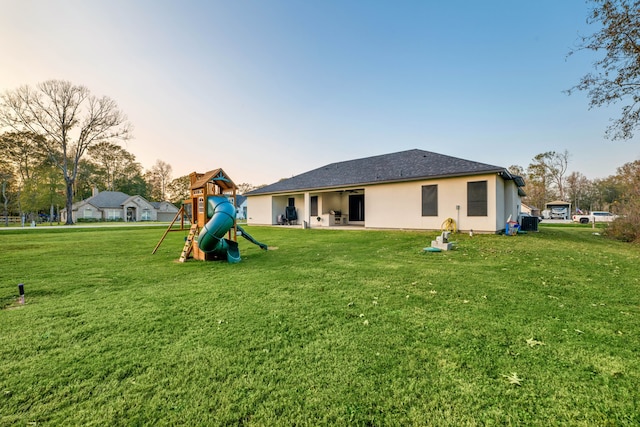 12 Rd 662, Dayton, TX 77535 - back of property at dusk with a playground, a lawn, stucco siding, and a shingled roof