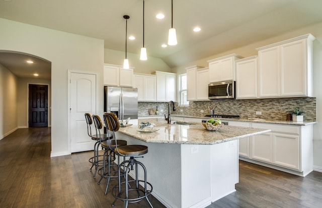 15898 Hayes Market Loop, Conroe, TX 77302 - kitchen featuring appliances with stainless steel finishes, backsplash, dark wood-type flooring, arched walkways, and vaulted ceiling