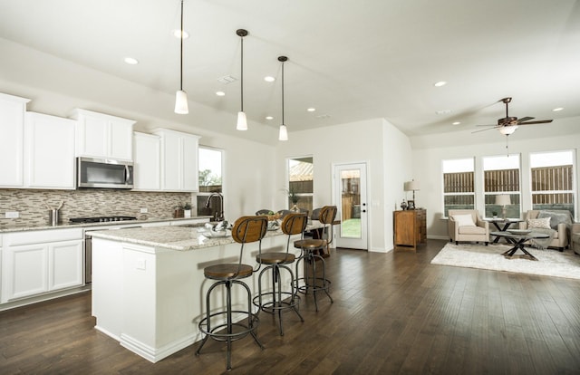 15898 Hayes Market Loop, Conroe, TX 77302 - kitchen with stainless steel microwave, recessed lighting, tasteful backsplash, an island with sink, and a ceiling fan
