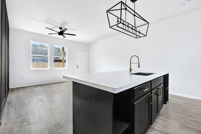 7939 Goode St, Houston, TX 77012 - kitchen with dark cabinetry, light countertops, ceiling fan, a center island with sink, and decorative light fixtures