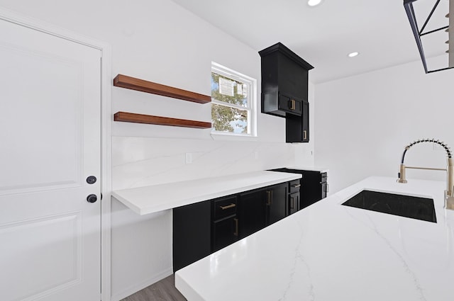 7939 Goode St, Houston, TX 77012 - kitchen with dark cabinetry, light stone countertops, open shelves, recessed lighting, and wood finished floors