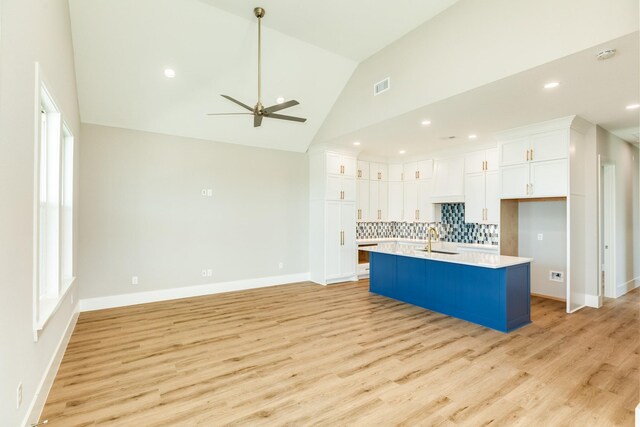 591 Pompano Dr, Freeport, TX 77541 - kitchen with light countertops, decorative backsplash, white cabinetry, light wood-style floors, and ceiling fan