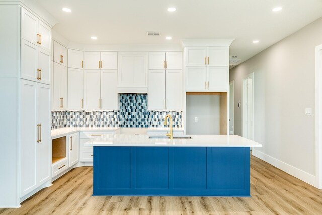 591 Pompano Dr, Freeport, TX 77541 - kitchen featuring light wood-style flooring, a center island with sink, backsplash, white cabinets, and recessed lighting