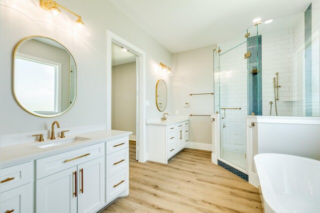 591 Pompano Dr, Freeport, TX 77541 - bathroom with a stall shower, two vanities, a soaking tub, and wood finished floors