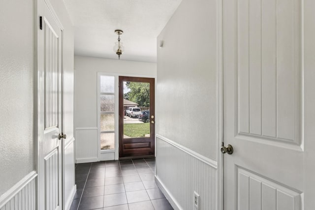 7927 Litchfield Ln, Spring, TX 77379 - entryway featuring wainscoting, dark tile patterned flooring, a decorative wall, and a textured wall