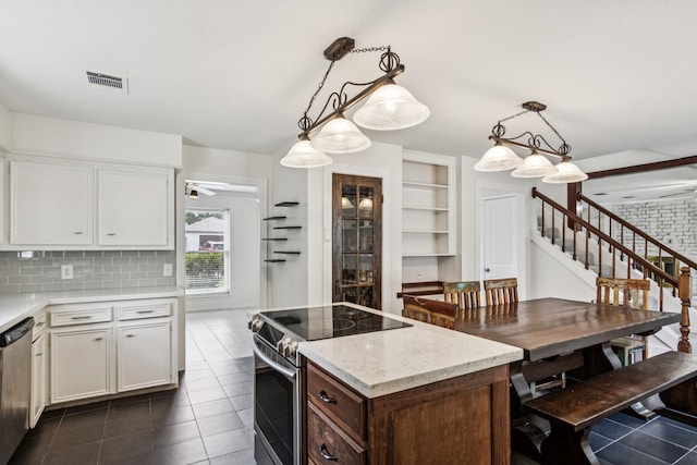 7927 Litchfield Ln, Spring, TX 77379 - kitchen with appliances with stainless steel finishes, white cabinets, dark tile patterned floors, and hanging light fixtures