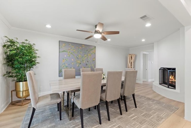 4406 Merwin St, Houston, TX 77027 - dining area featuring a multi sided fireplace, light wood-style flooring, ceiling fan, crown molding, and recessed lighting