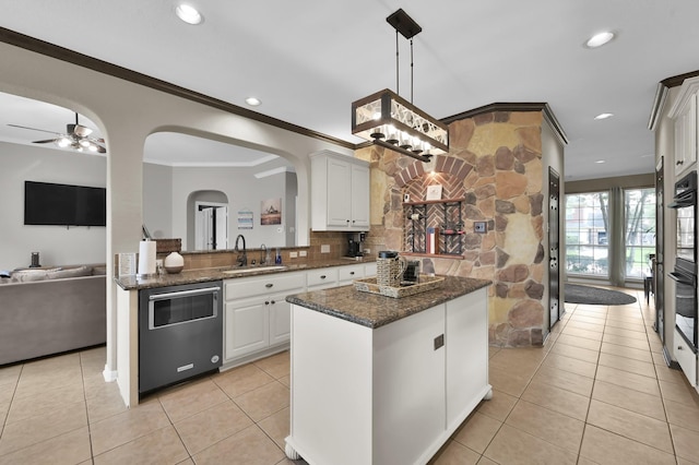 1415 Kennoway Park Dr, Spring, TX 77379 - kitchen with arched walkways, white cabinets, a kitchen island, light tile patterned floors, and ornamental molding