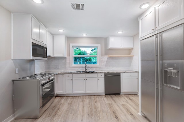 5858 Beldart St, Houston, TX 77033 - kitchen featuring appliances with stainless steel finishes, light wood-style flooring, open shelves, white cabinetry, and recessed lighting
