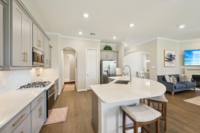2018 Oxley Manor Ln, Richmond, TX 77469 - kitchen featuring arched walkways, appliances with stainless steel finishes, gray cabinetry, ornamental molding, and decorative backsplash