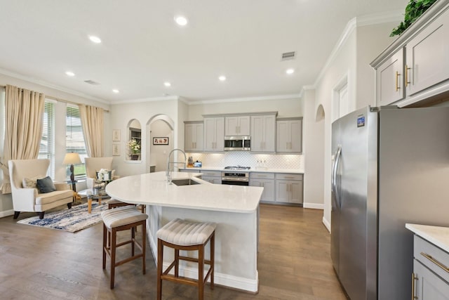 2018 Oxley Manor Ln, Richmond, TX 77469 - kitchen with stainless steel appliances, gray cabinetry, ornamental molding, decorative backsplash, and a breakfast bar