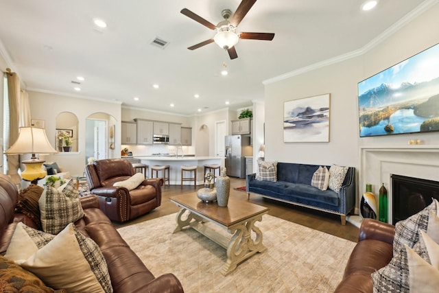 2018 Oxley Manor Ln, Richmond, TX 77469 - living room featuring arched walkways, a ceiling fan, crown molding, wood finished floors, and recessed lighting