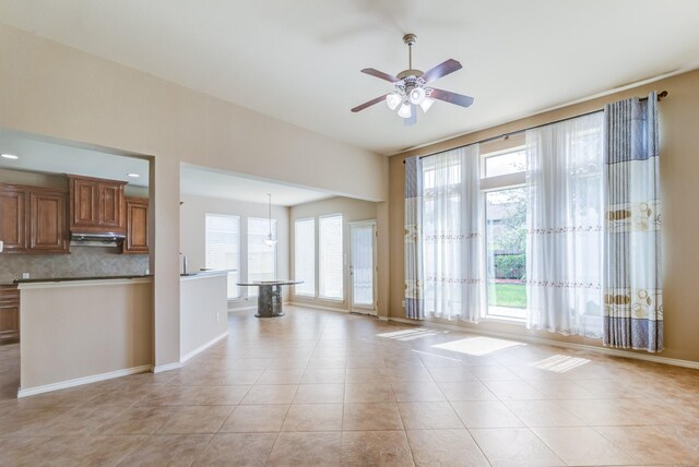 6103 Timbermoss Ct, League City, TX 77573 - kitchen featuring under cabinet range hood, brown cabinets, a ceiling fan, tasteful backsplash, and light tile patterned floors