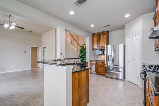 6103 Timbermoss Ct, League City, TX 77573 - kitchen featuring black appliances, brown cabinets, ceiling fan, dark stone counters, and light tile patterned floors