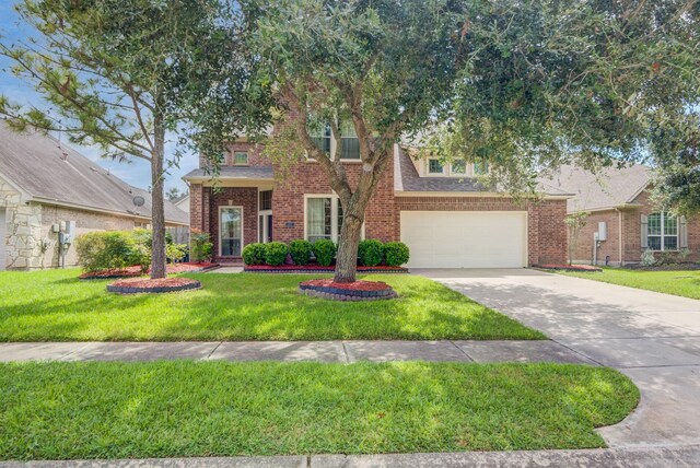6103 Timbermoss Ct, League City, TX 77573 - obstructed view of property with concrete driveway, an attached garage, a front yard, and brick siding