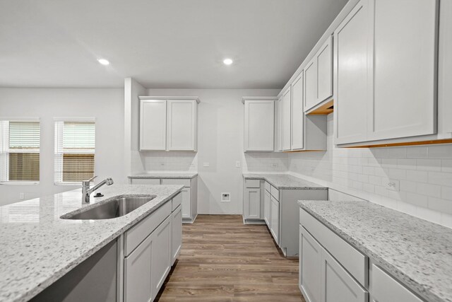 10713 Blocker Ct, Bryan, TX 77801 - kitchen with light stone counters, wood finished floors, decorative backsplash, recessed lighting, and white cabinetry