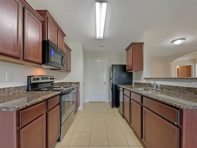 8839 Hazel Rose Sky Dr, Humble, TX 77338 - kitchen with black appliances, light tile patterned flooring, arched walkways, dark stone countertops, and a peninsula